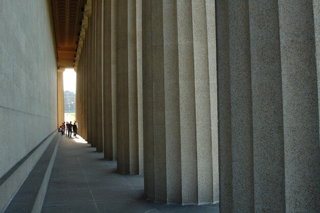 Photo people walking in corridor along pillars and wall