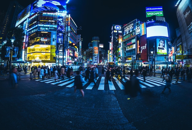 Foto gente che cammina su una strada illuminata di notte a shibuya, tokyo, giappone