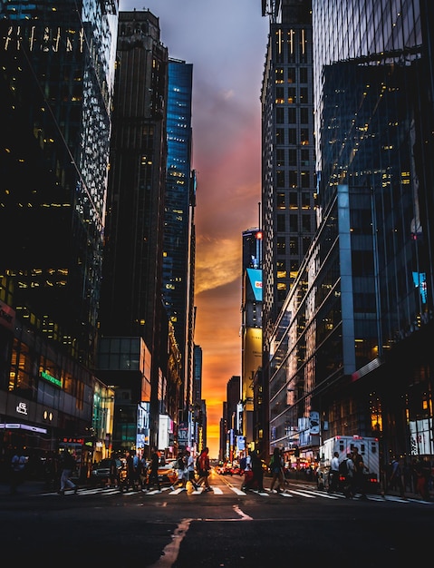 People walking on illuminated city street during sunset