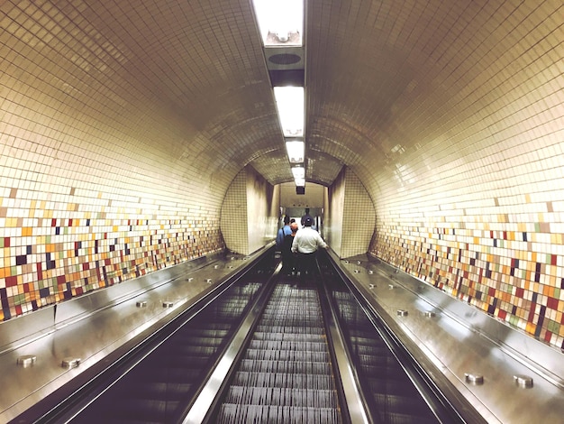 Foto gente che cammina su una stazione della metropolitana illuminata