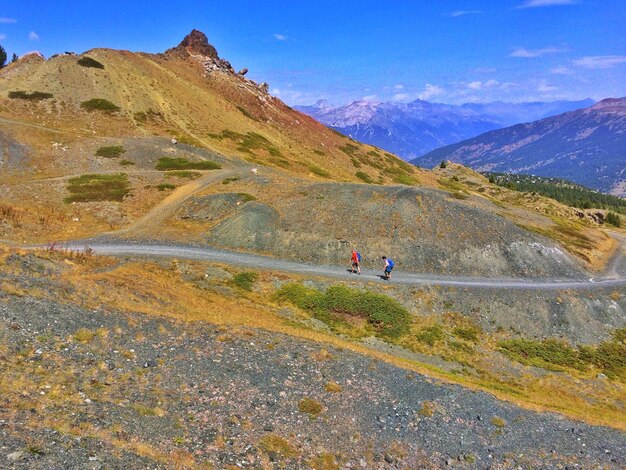 People walking on mountain road against sky