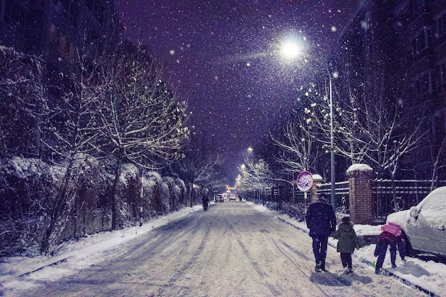 People walking on road in winter at night