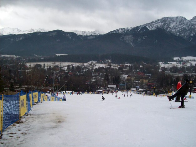 People walking on snowcapped mountain against sky