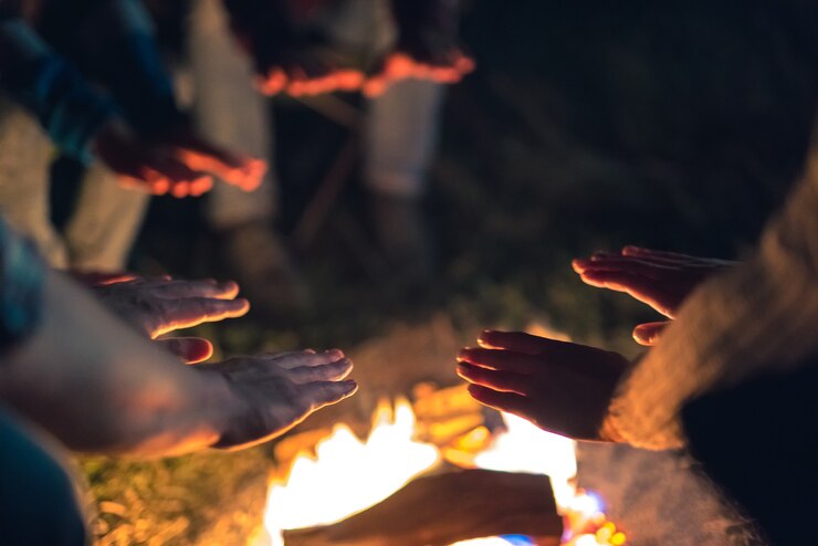 焚き火の近くで手を温める人々。夕方の夜