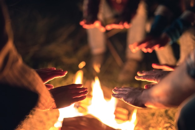 焚き火の近くで手を温める人々。夕方の夜