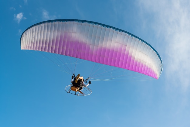 people was playing a Paramotor flying on the blue sky background