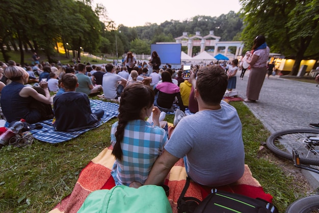 Люди смотрят фильм в кинотеатре под открытым небом в городском парке