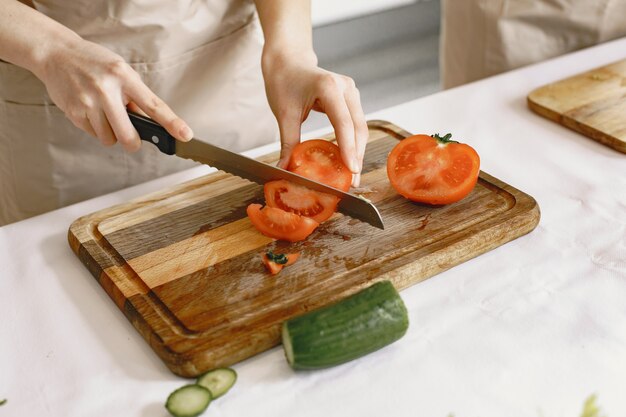 新鮮な野菜のサラダを作っている人。エプロンのアジア人。