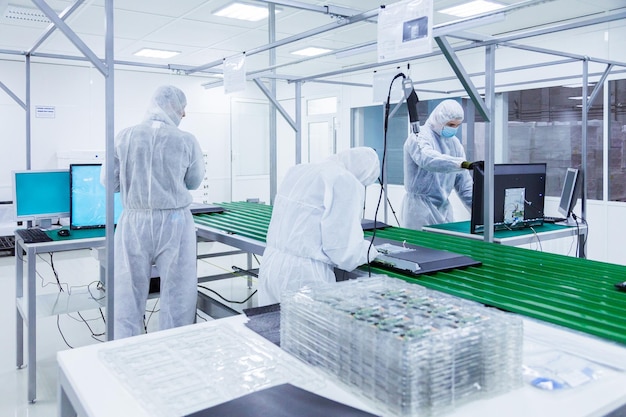 People in white isolating costumes working in laboratory