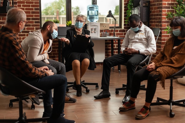 People with addiction meeting at aa group therapy session to\
receive counseling from therapist. patients with face masks\
attending aa support program during covid 19 pandemic.