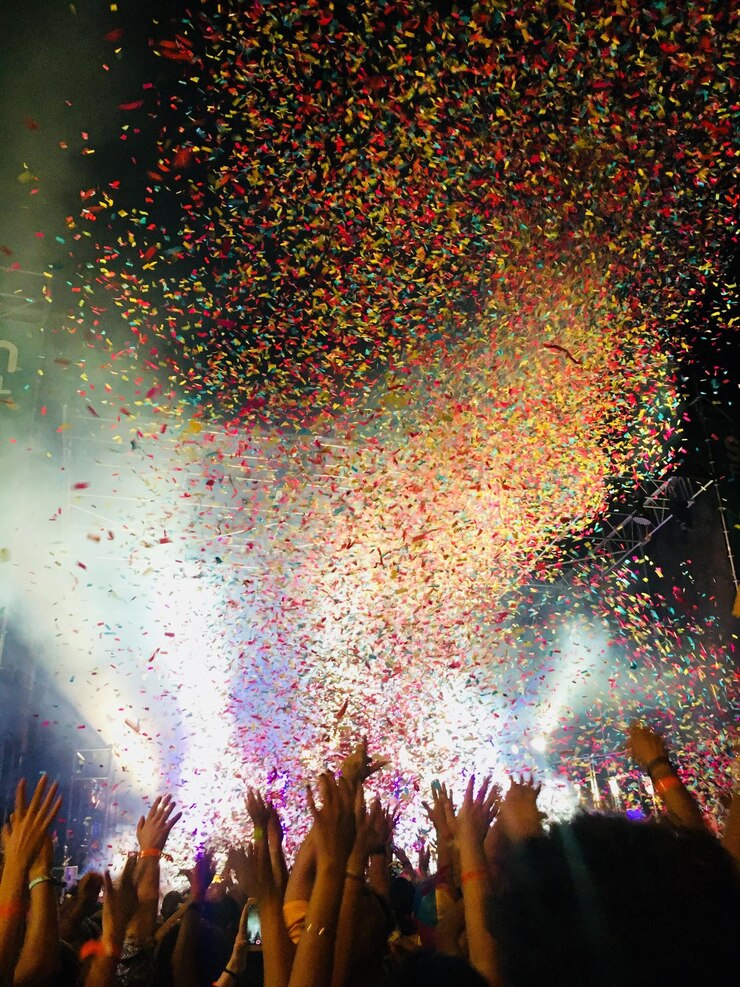 Photo people with arms raised against confetti flying during music concert