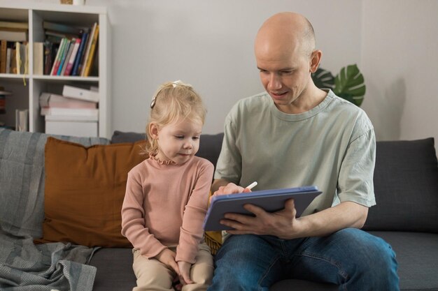 人工内耳システムの子供の勉強をしている人は、タブレットでビデオを使って父親と一緒に聞いて勉強しています