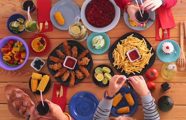 ダイニングテーブルに座って飲み物を飲む人々 テーブルの上の食べ物 テーブルの上の食べ物 ファーストフードを食べる人々