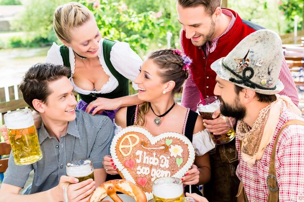 Photo people with gingerbread heart in beer garden drinking beer in summer