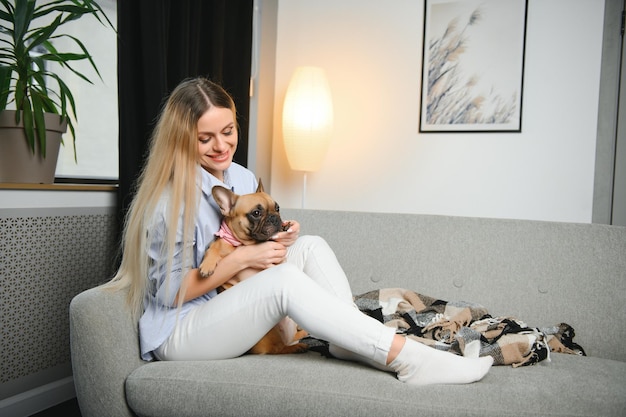 People with pets concept Smiling woman playing on couch with dog at home