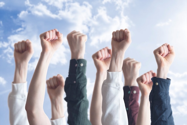 The people with raised hands fists in the air, as symbol of protest for equality. freedom.