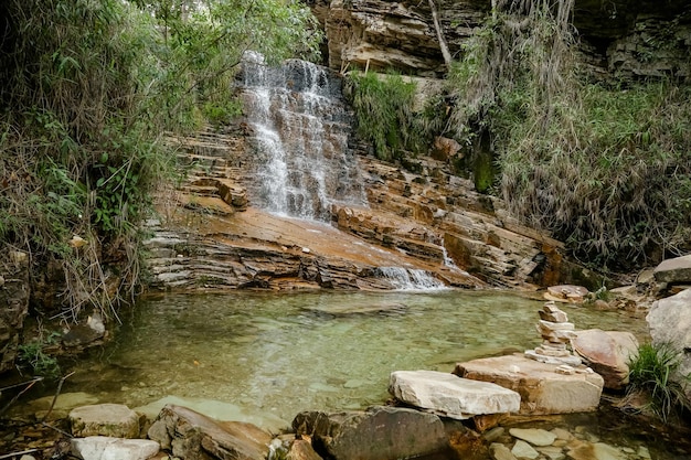 People with witches\' hats on a trip to a secret logoa among the\
rocks and waterfalls in the mountain