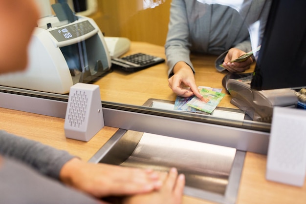 people, withdrawal, money, saving and finance concept - clerk counting swiss francs cash at bank office or currency exchanger