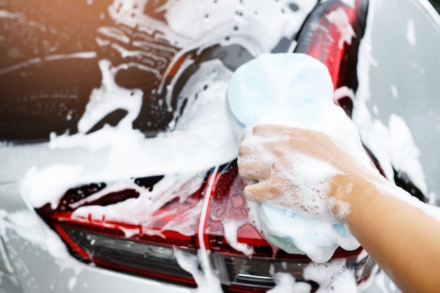People worker man holding hand blue sponge and bubble foam\
cleanser window for washing car. concept car wash clean. leave\
space for writing messages.