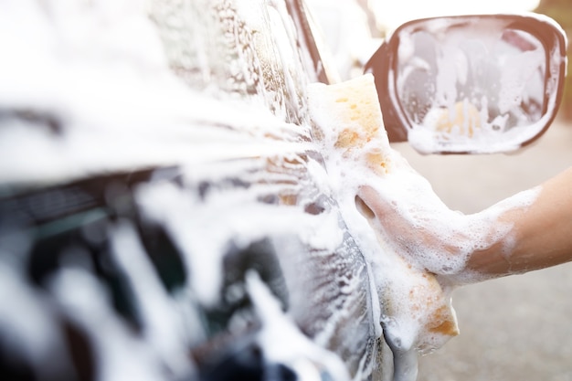 People worker man holding hand yellow sponge and bubble foam
cleanser window for washing car. concept car wash clean. leave
space for writing messages.