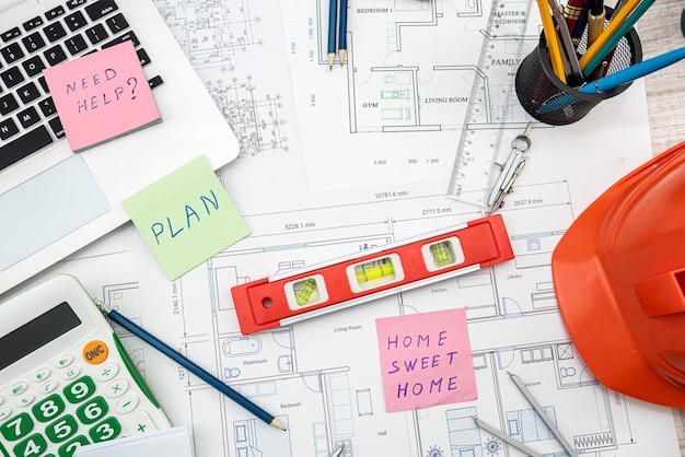 People working with construction drawings and tools at a wooden table