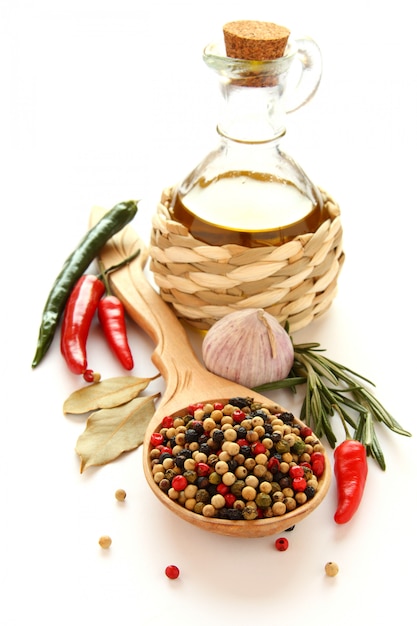Peper op houten lepel, olijfolie, chinese knoflook, kruiden en specerijen in wit