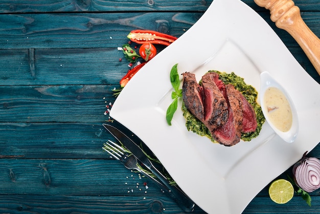 Peper Steak van kalfsvlees met spinazie Op een houten ondergrond Bovenaanzicht Kopieer de ruimte