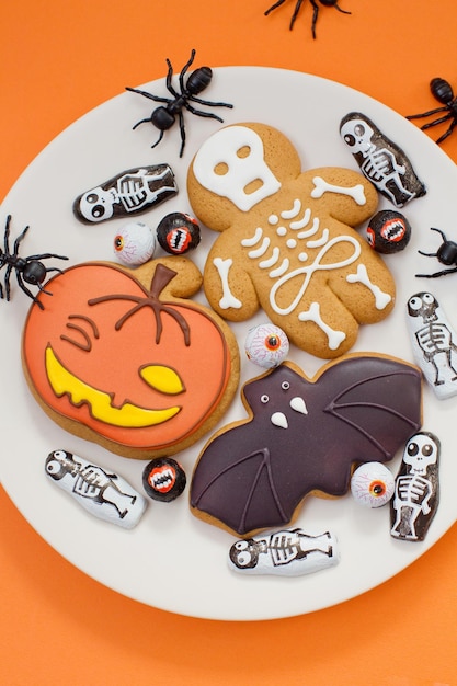 Peperkoek Halloween-koekjes en zwarte mierendecoratie op een oranje achtergrond Halloween-concept