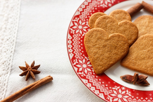 Peperkoek hartvormige koekjes met pijpjes kaneel en anijsplantsterren op een rode plaat