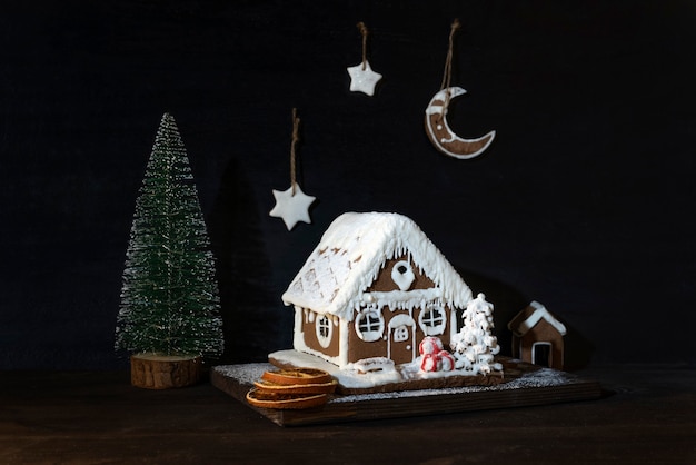 Peperkoek huis en kleine kerstboom op donkere achtergrond. Kerst samenstelling.