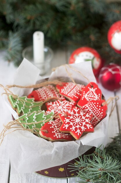 Peperkoek in een blikken doos op de achtergrond met Kerstmisspeelgoed, een kaars en dennentakken.