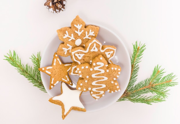 Peperkoek peperkoek op een bord op een lichte achtergrond, kerstboomtak, kegel. het concept van voedsel voor kerstmis.