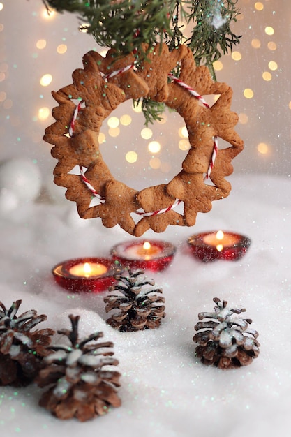 Peperkoekengelen op een kerstboom met een rood lint, hangend boven kaarsen en kegels in de sneeuw