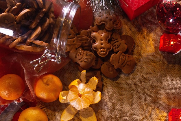 Peperkoekkoekjes in een pot. Mandarijnen zorgen voor een nieuwjaarsstemming. Feestelijke lantaarns op de voorgrond. Dit alles tegen de achtergrond van linnen materiaal.