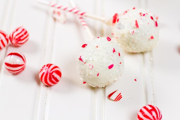 Pepermunt-chocoladecake-pops gedoopt in witte chocolade en stukjes snoepgoed.