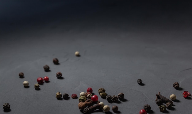 Pepper mix and cloves. Black, red and white peppercorns isolated on black stone background. Close-up