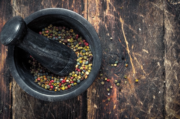 Pepper in a mortar with a pestle. On a wooden table.