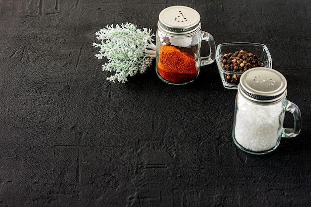 Pepper and salt glass shakers on a black concrete backgroun with copy space.