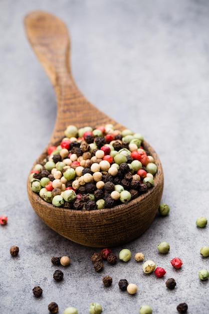 Peppercorn mix in a wooden bowl on grey table