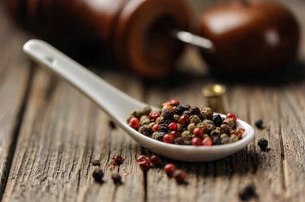 Peppercorn in a spoon on wooden background