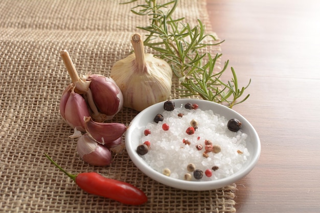 Peppercorns black pepper white pepper with garlic rosemary and chili pepper in the background