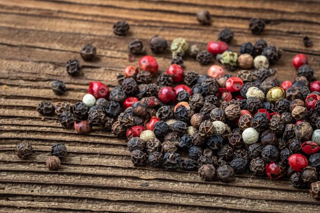 Peppercorns on dark rustic wooden background Mix of different peppers