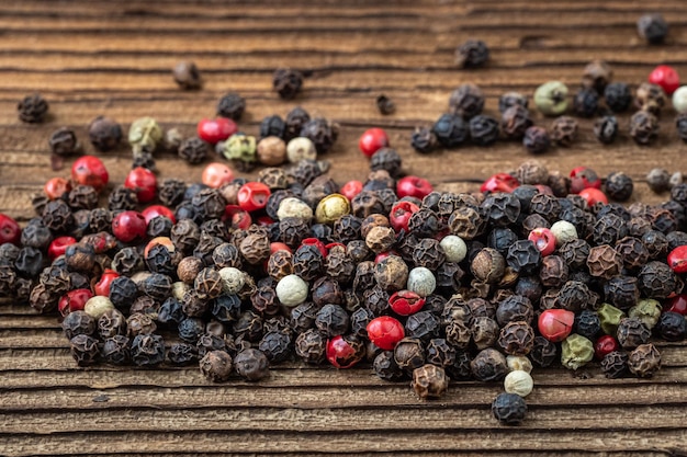 Peppercorns on dark rustic wooden background Mix of different peppers