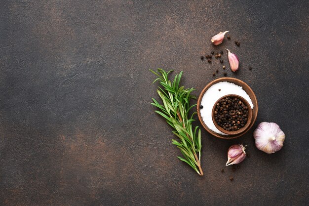 Peppercorns, garlic and fresh rosemary on a concrete background.