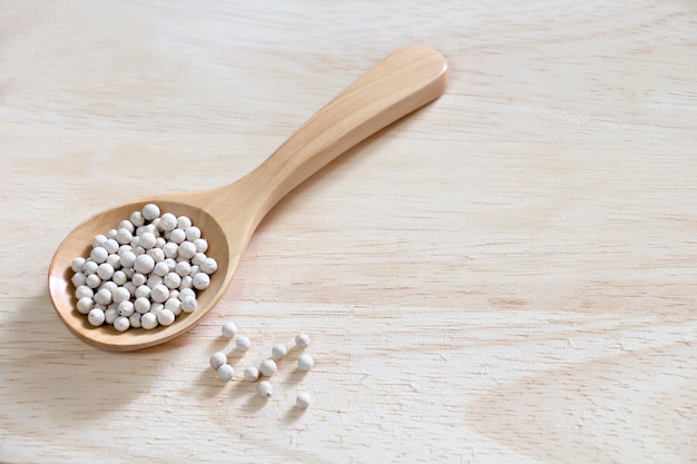 Peppercorns in spoon wood on wooden.