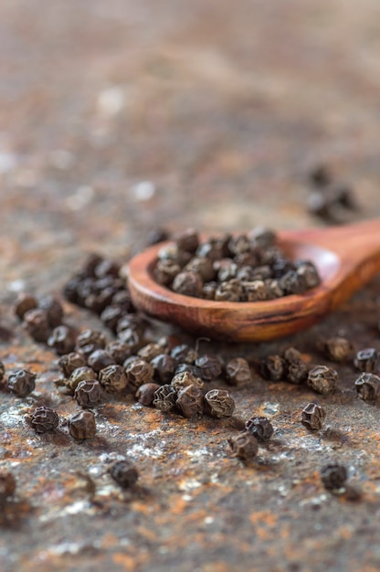 Peppercorns in wooden spoon on texture