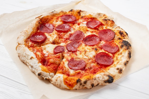 Pepperoni pizza in a box on a white wooden table