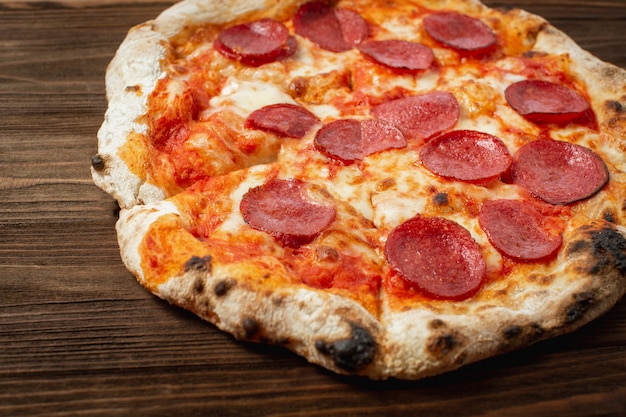 Pepperoni pizza in a box on a white wooden table