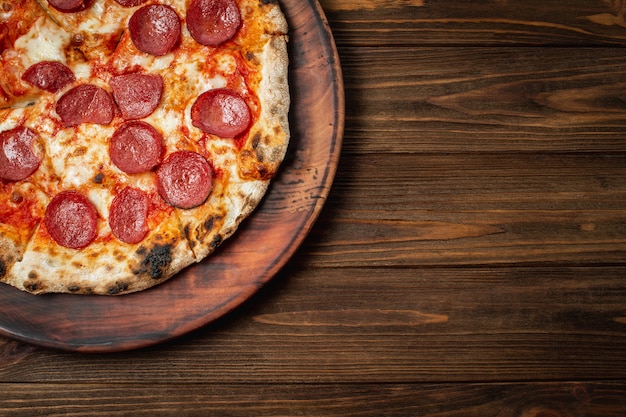 Pepperoni pizza in a box on a white wooden table