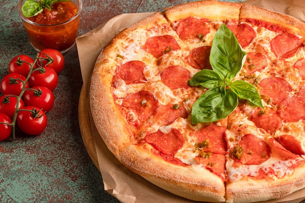 Pepperoni pizza on a concrete background with basil